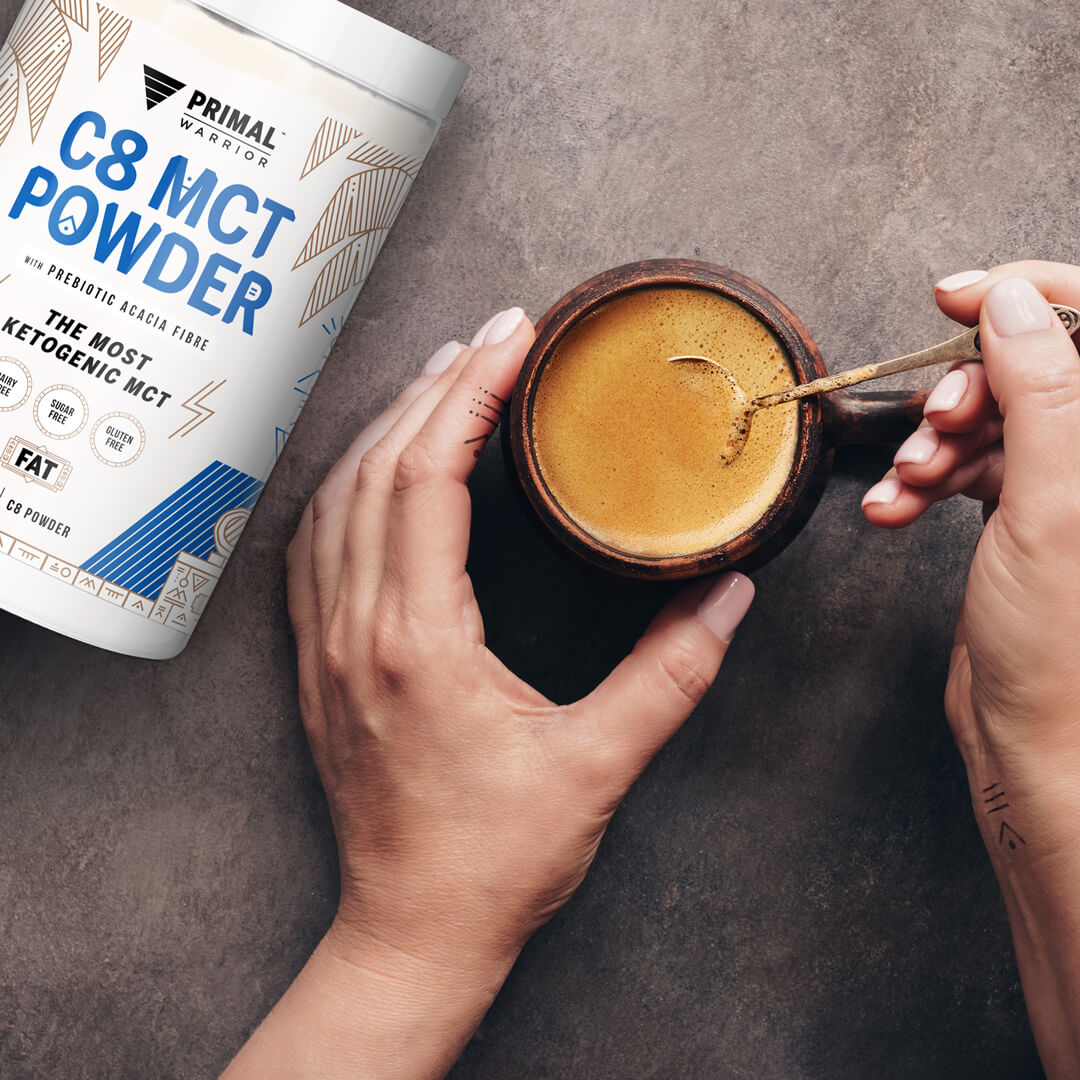 Image of a woman's hands stirring a hot cup of coffee with Primal Warrior C8 MCT Creamer