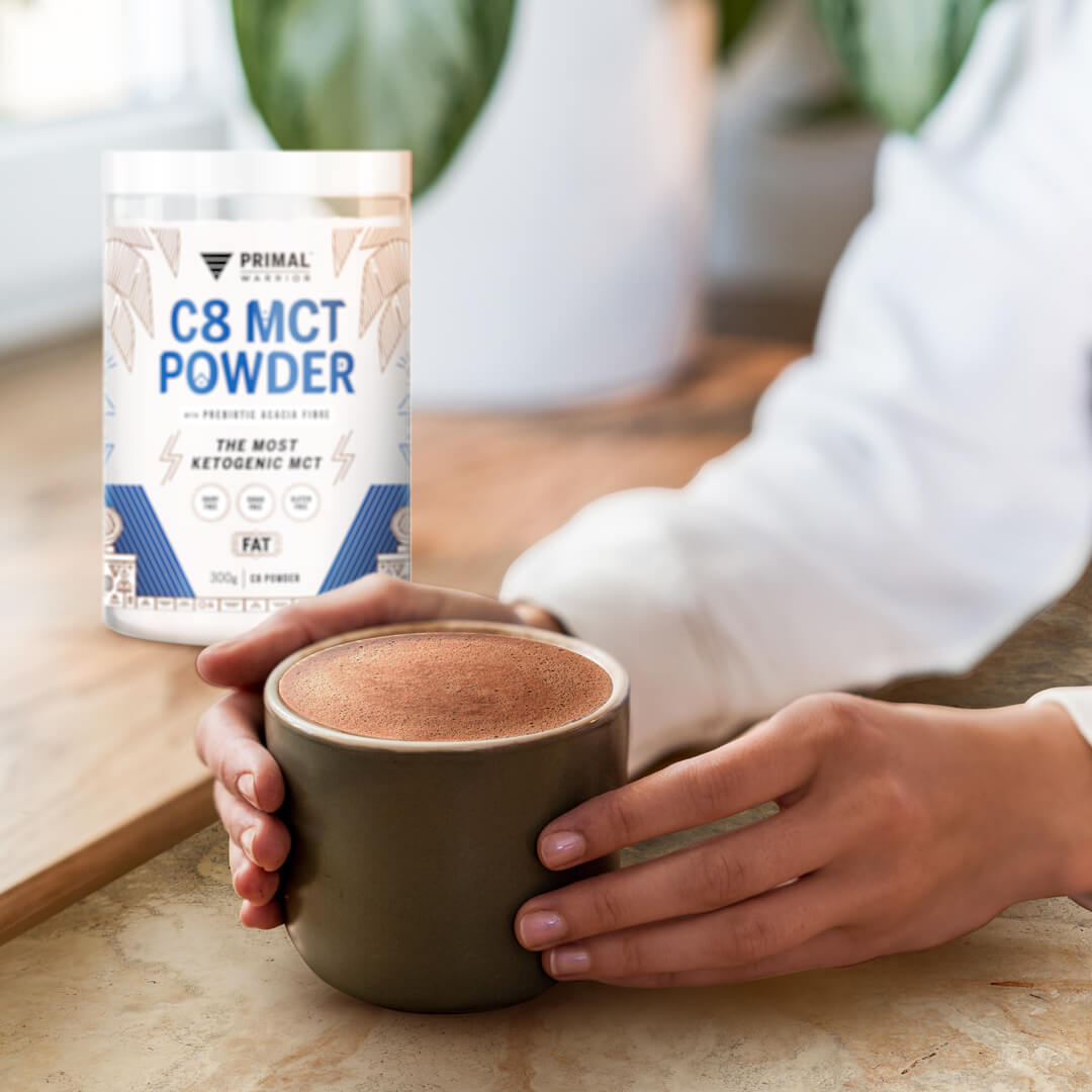 Image of a woman's hands holding a cup of hot chocolate with Primal Warrior C8 MCT Creamer