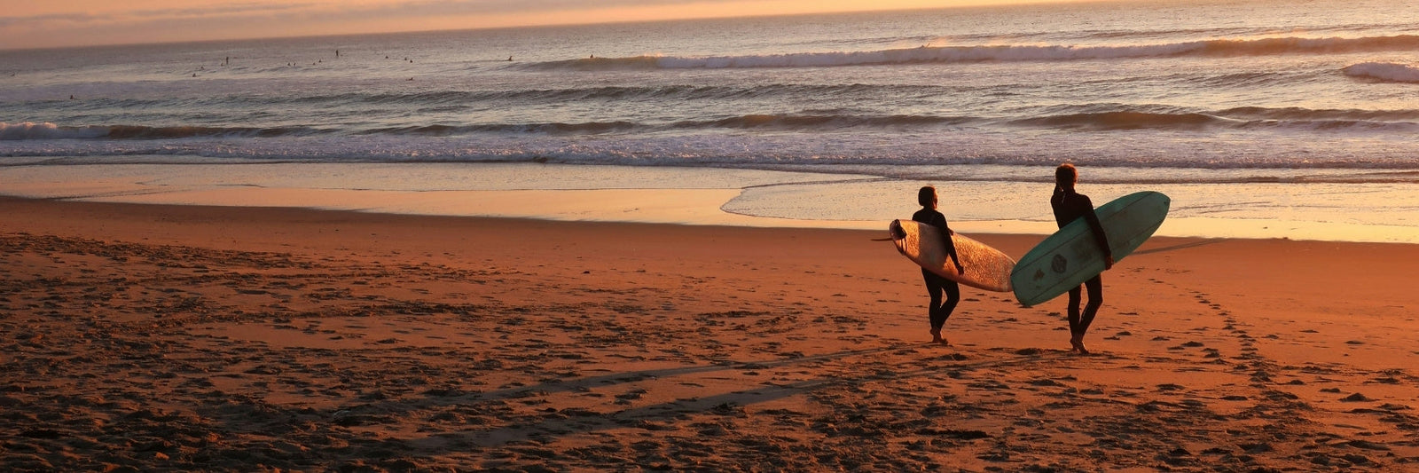 Two surfers on the beach at sunset